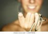 A close up of a woman's hand. She is holding out a contact lens with her index finger and folded pair of eyeglasses with her pinky finger.