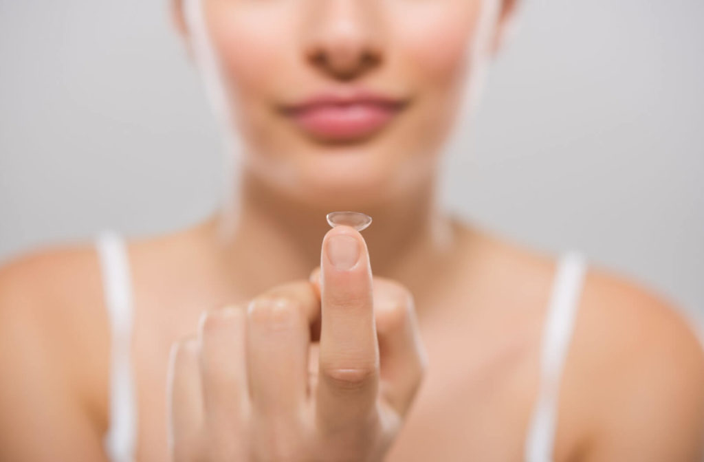 Close-up of a woman’s left hand holding a contact lens.
