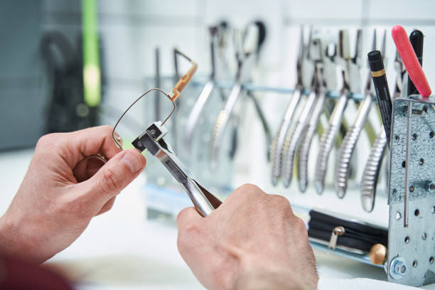 eyewear maintenance - Close up of man hands using professional optical pliers while fixing eyeglasses frame